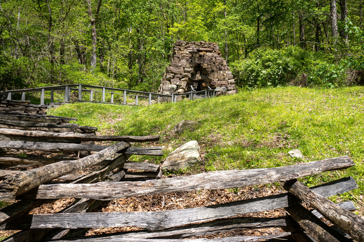 Historic stone chimney and split-rail fence in a wooded setting representing Clairfield, Tennessee