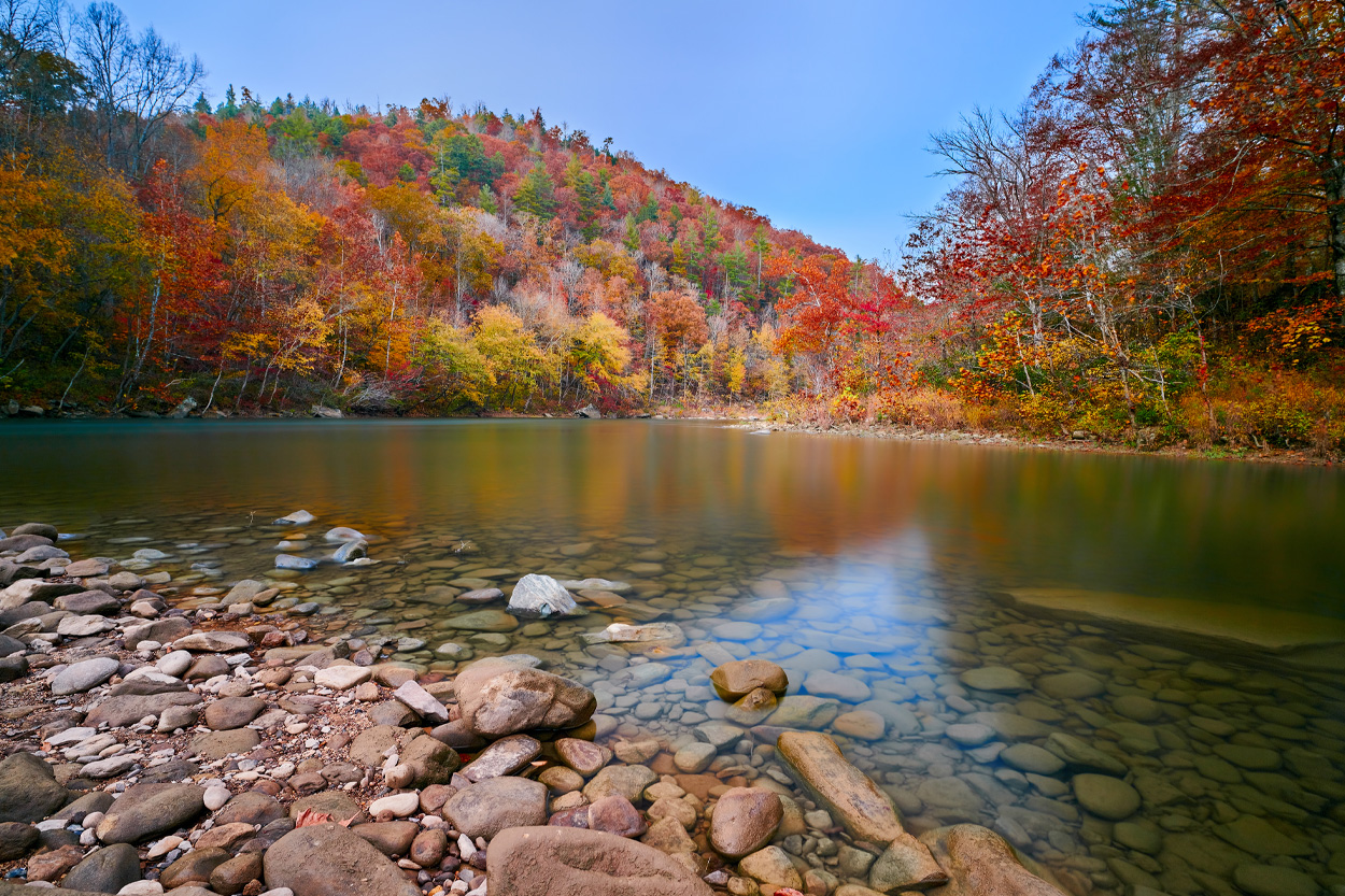 Clear mountain river bordered by colorful autumn trees representing Eagan, Tennessee