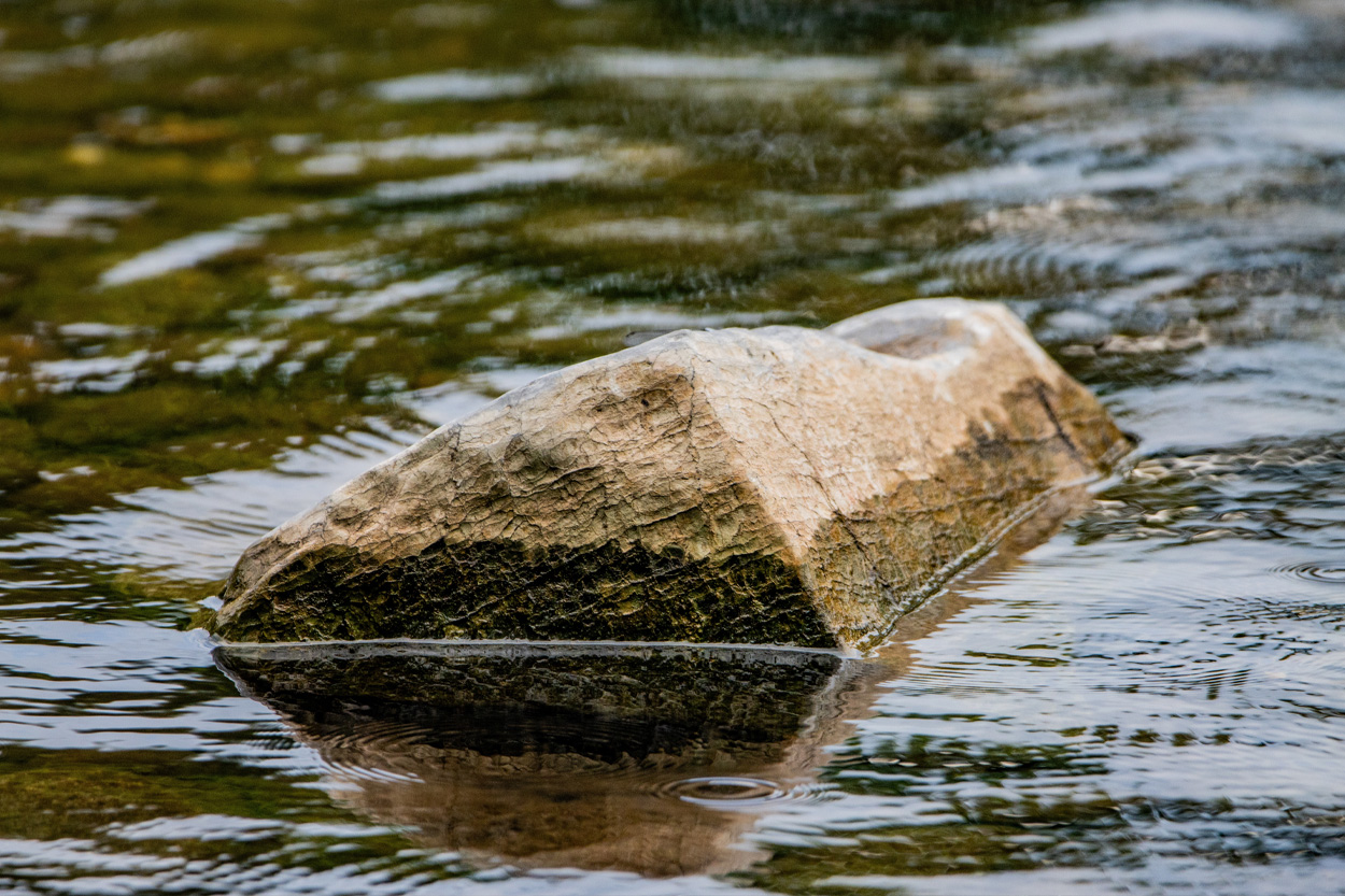 Large rock surrounded by flowing water representing Lone Mountain, Tennessee