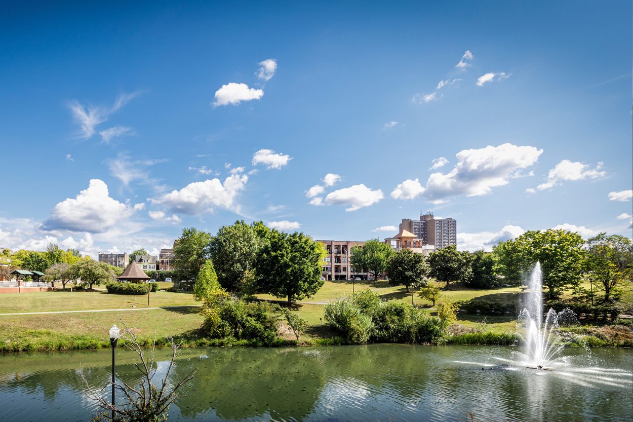 Landscaped park with a pond, fountain, walking paths, and downtown Maryville, Tennessee, in the background