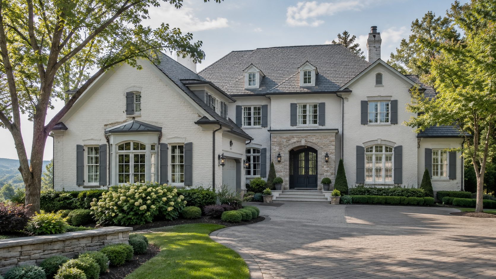 Elegant Knoxville luxury home with light stone architecture, blue-gray shutters, mature trees, and manicured landscaping.