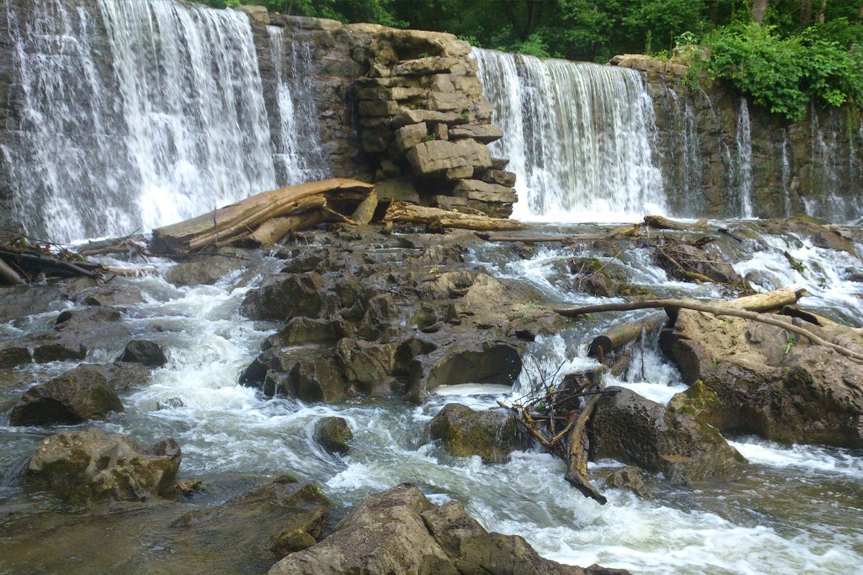 Waterfall flowing over a stone ledge and rocky stream representing Rogersville, Tennessee